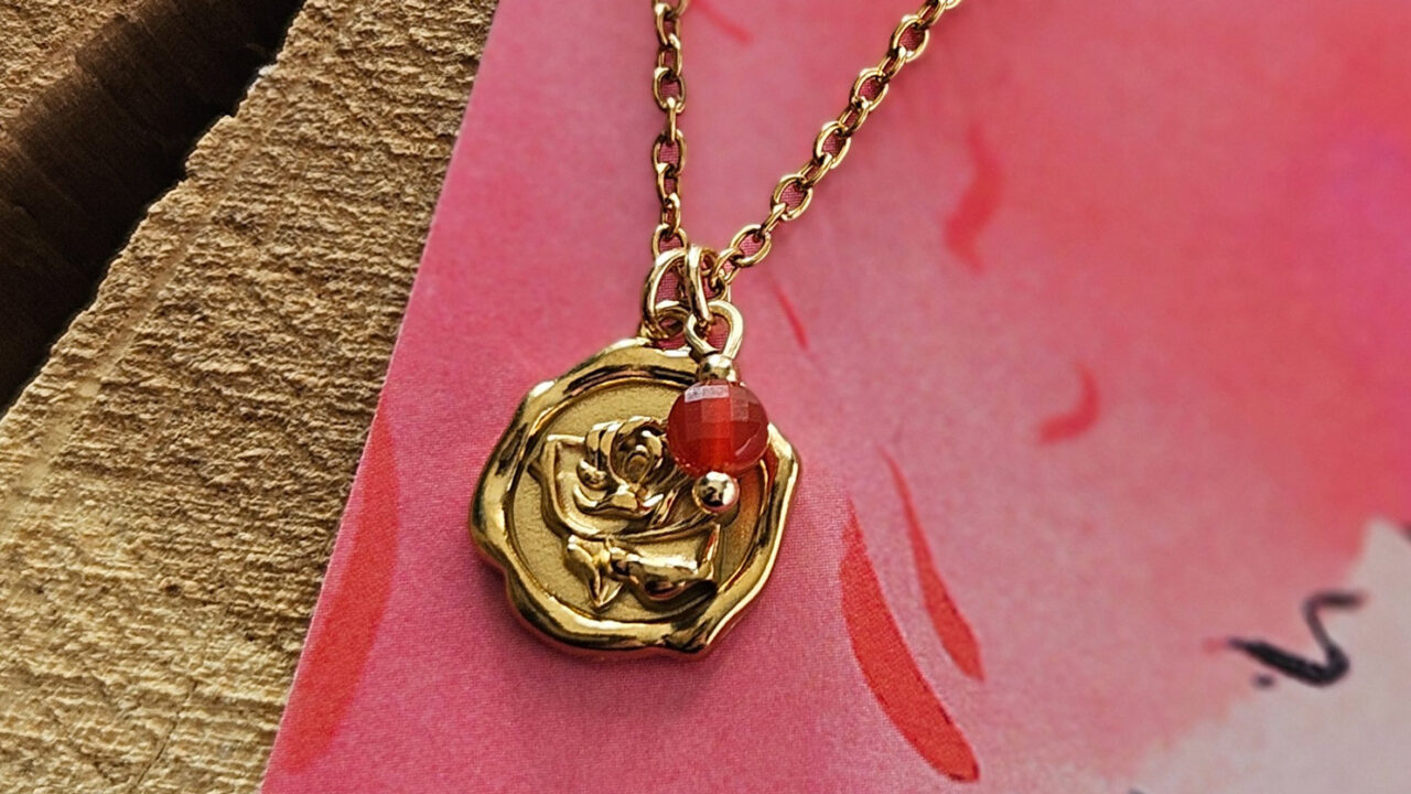 łańcuszek z czerwonym karneolem i metalową zawieszką medalionem w złotym kolorze