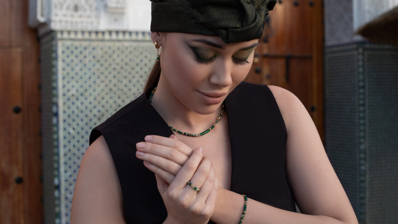 biżuteria z zielonych kamieni naturalnych do czarnej sukienki, piękna kobieta z mocnym makijażem i czarną chustą na głowie